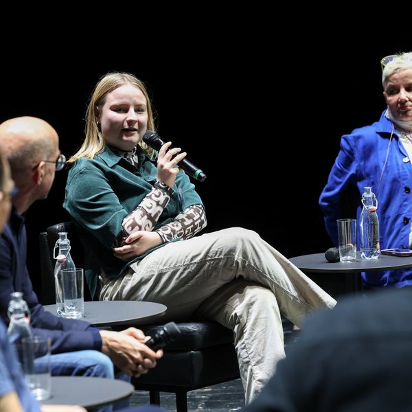 Eine Frau spricht bei der Podiumsdiskussion ins Mikrofon.