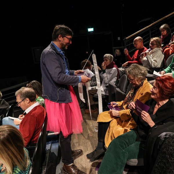 Uwe Gössel als Fee verkleidet verteilt Karten im Publikum.