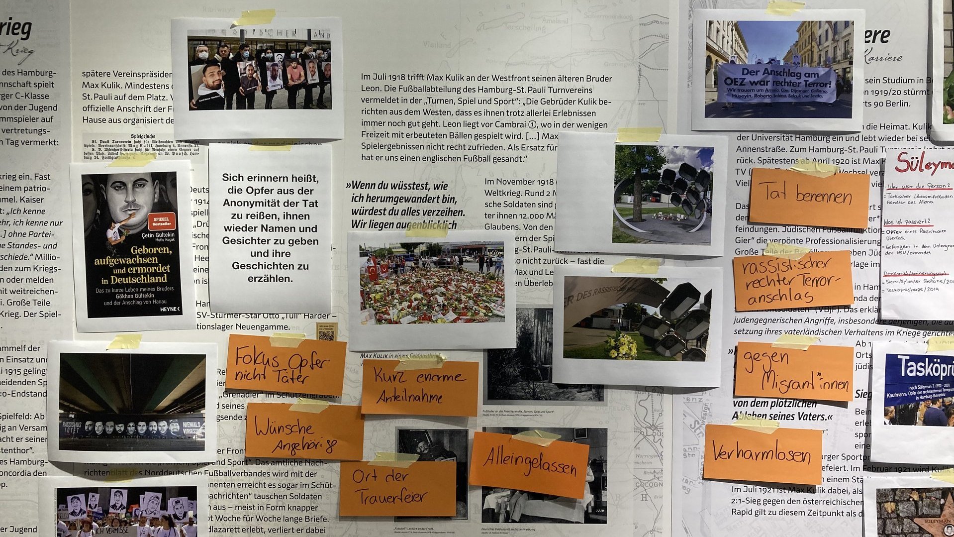 Bilder, Zitate und beschriftete Kärtchen kleben an einer Wand. Auf den Bildern sind trauernde Menschen und Denkmäler.