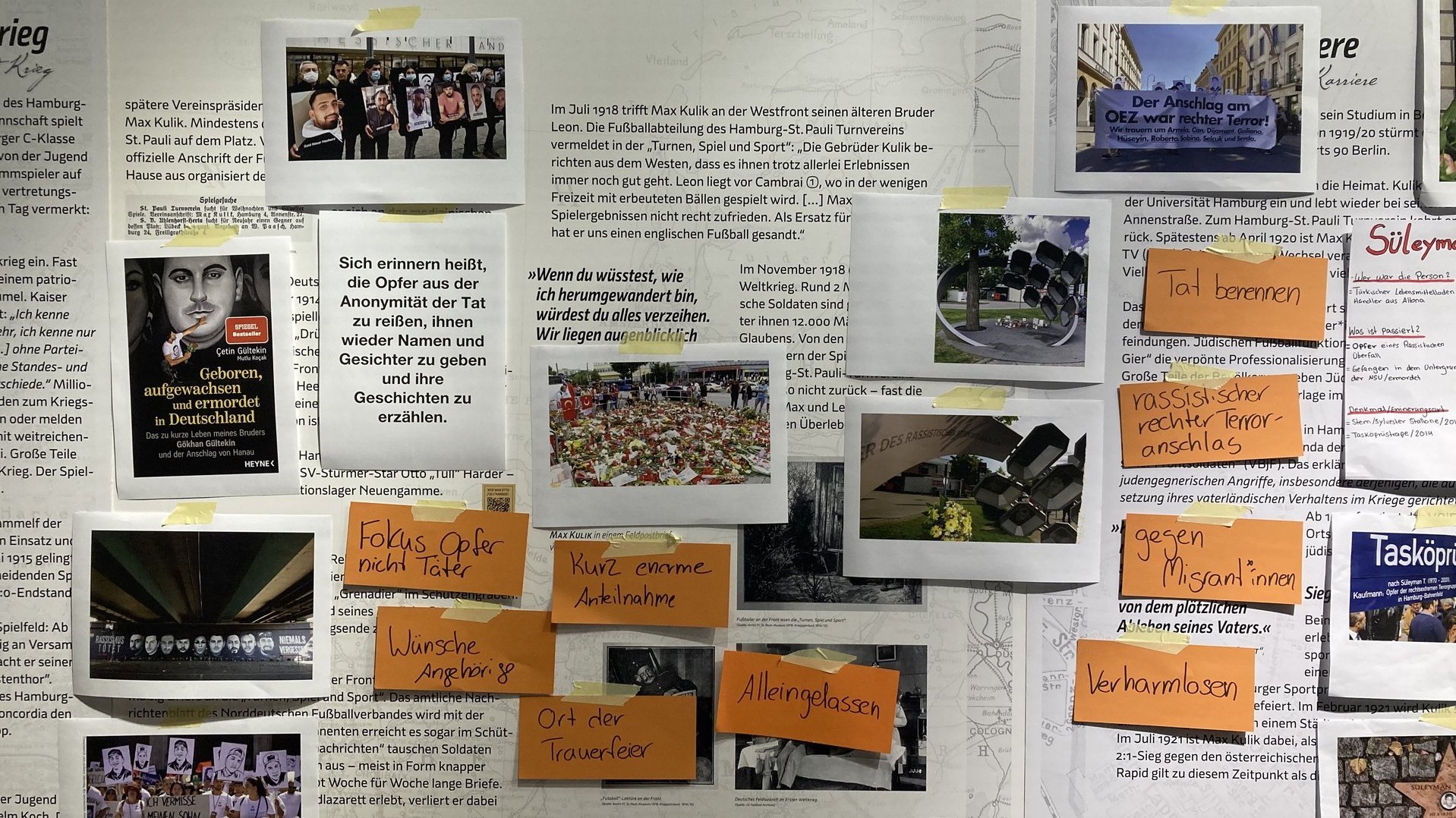 Bilder, Zitate und beschriftete Kärtchen kleben an einer Wand. Auf den Bildern sind trauernde Menschen und Denkmäler.