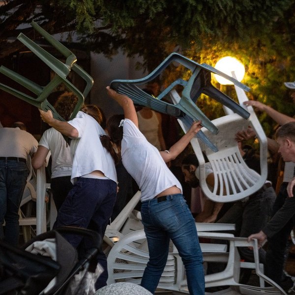 Junge Menschen tanzen mit Plastikstühlen.