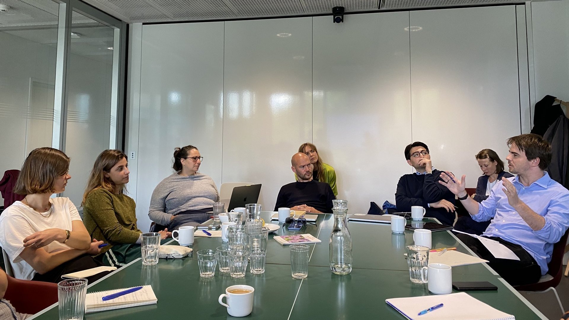 Eine Gruppe Menschen an einem Konferenztisch diskutiert.