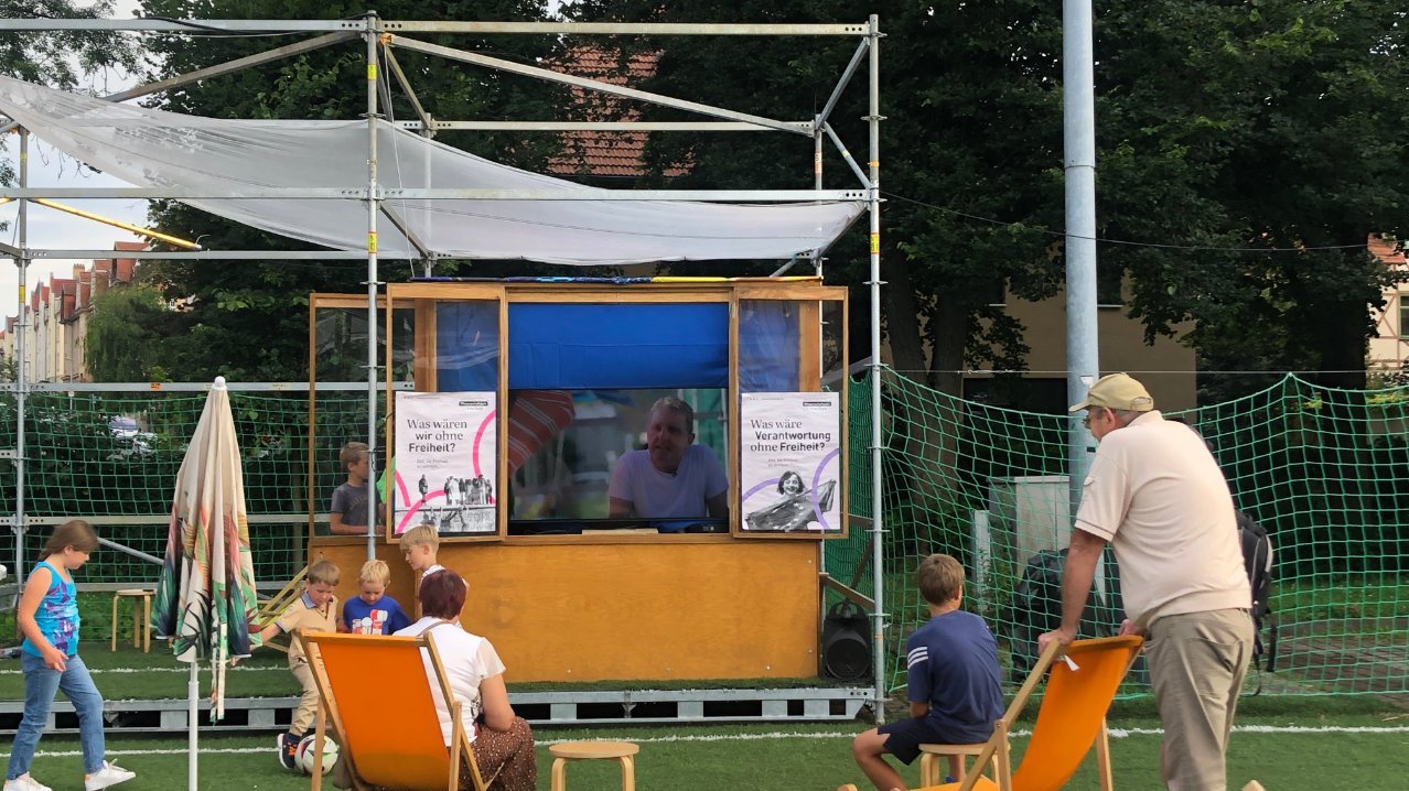 Kinder und ein Mann schauen einen Film am Kiosk.