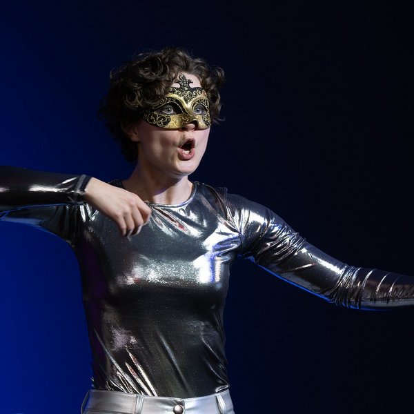 Eine maskierte Schauspielerin gestikuliert.