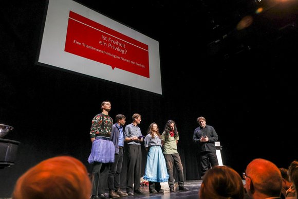 Darstellende und Projektverantwortliche stehen auf der Theaterbühne.