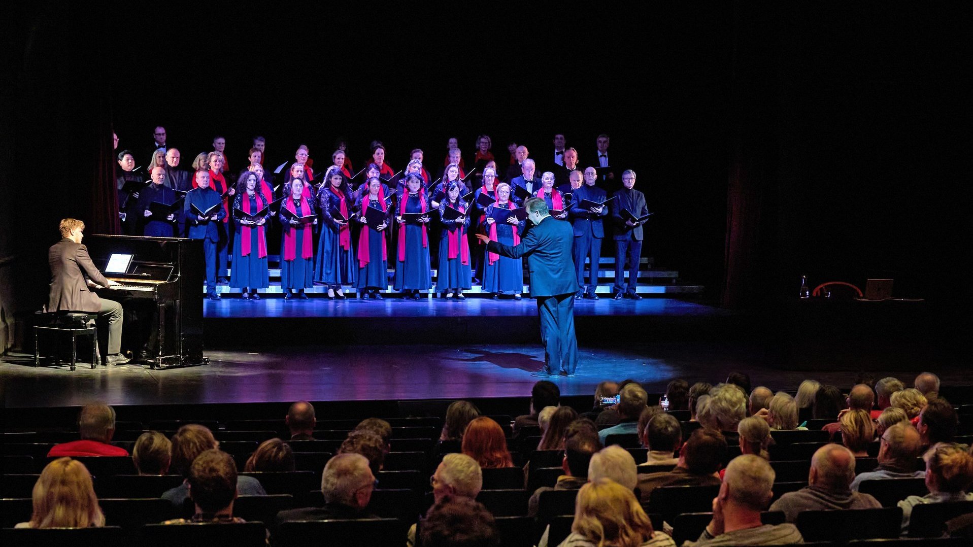 Ein Chor singt begleitet vom Klavier auf der Bühne vor Publikum.