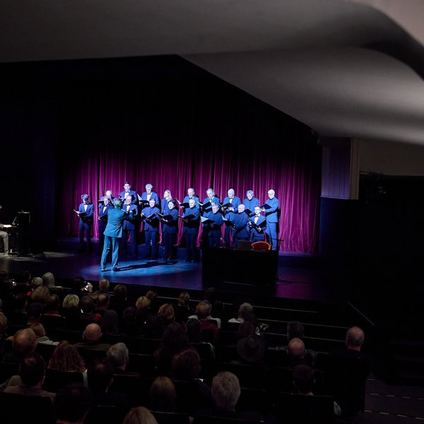 Der Chor singt begleitet vom Klavier auf der Bühne vor Publikum.