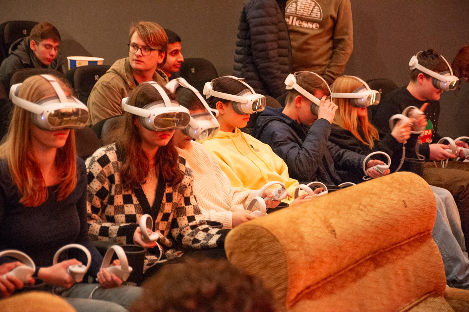 Sieben Kinder sitzen in einer Reihe, sie tragen VR-Brillen. 