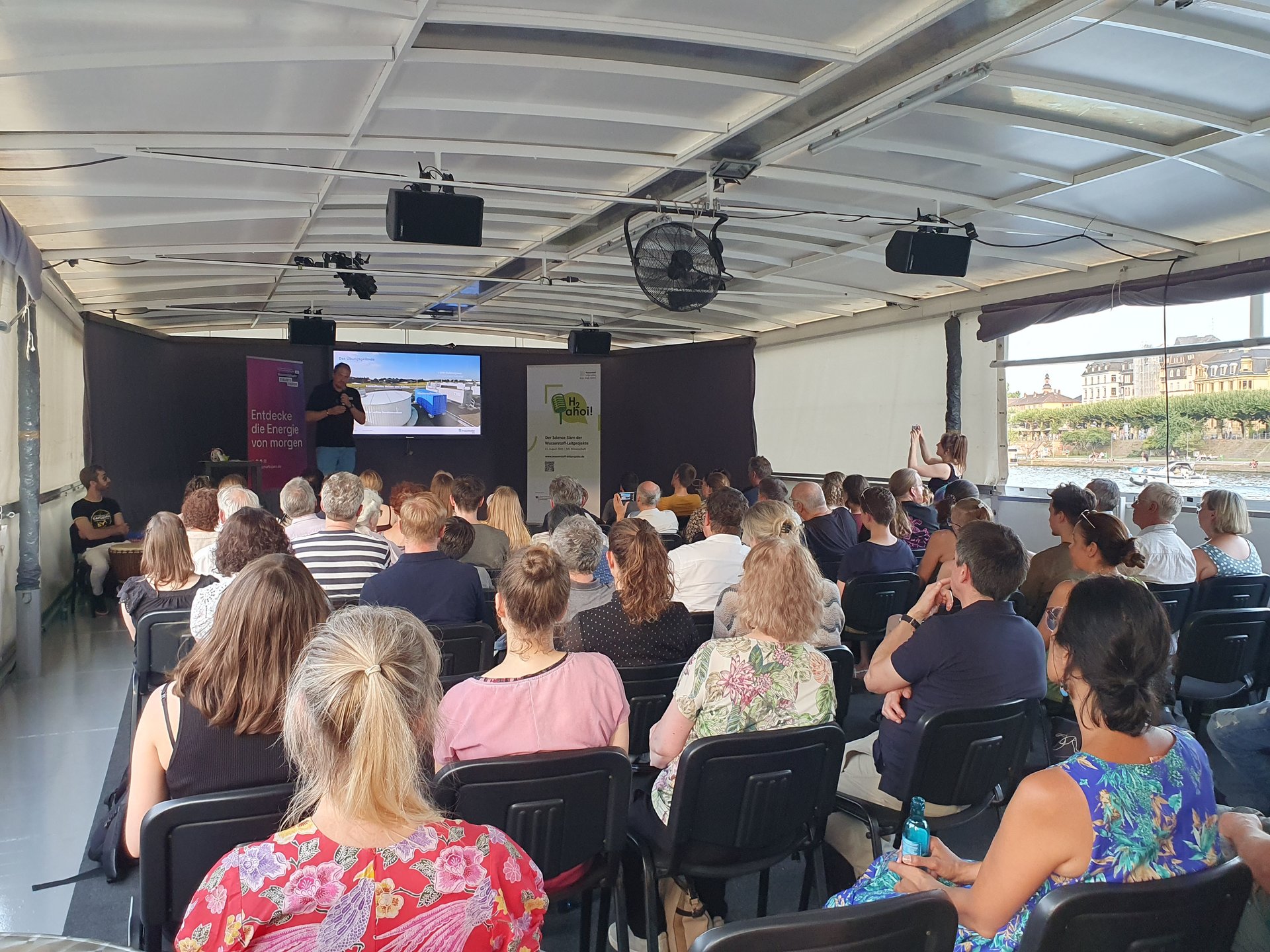 Ein Forscher stellt vor dem Publikum an Bord der MS Wissenschaft seine Forschungsergebnisse vor.