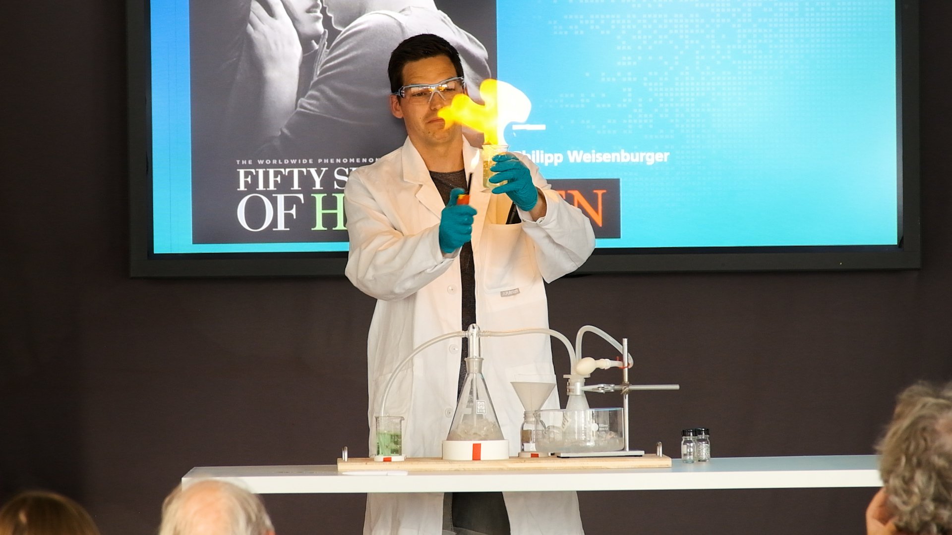 Philipp Weisenburger mit Schutzbrille und Kittel entzündet eine Flamme mit Wasserstoff.