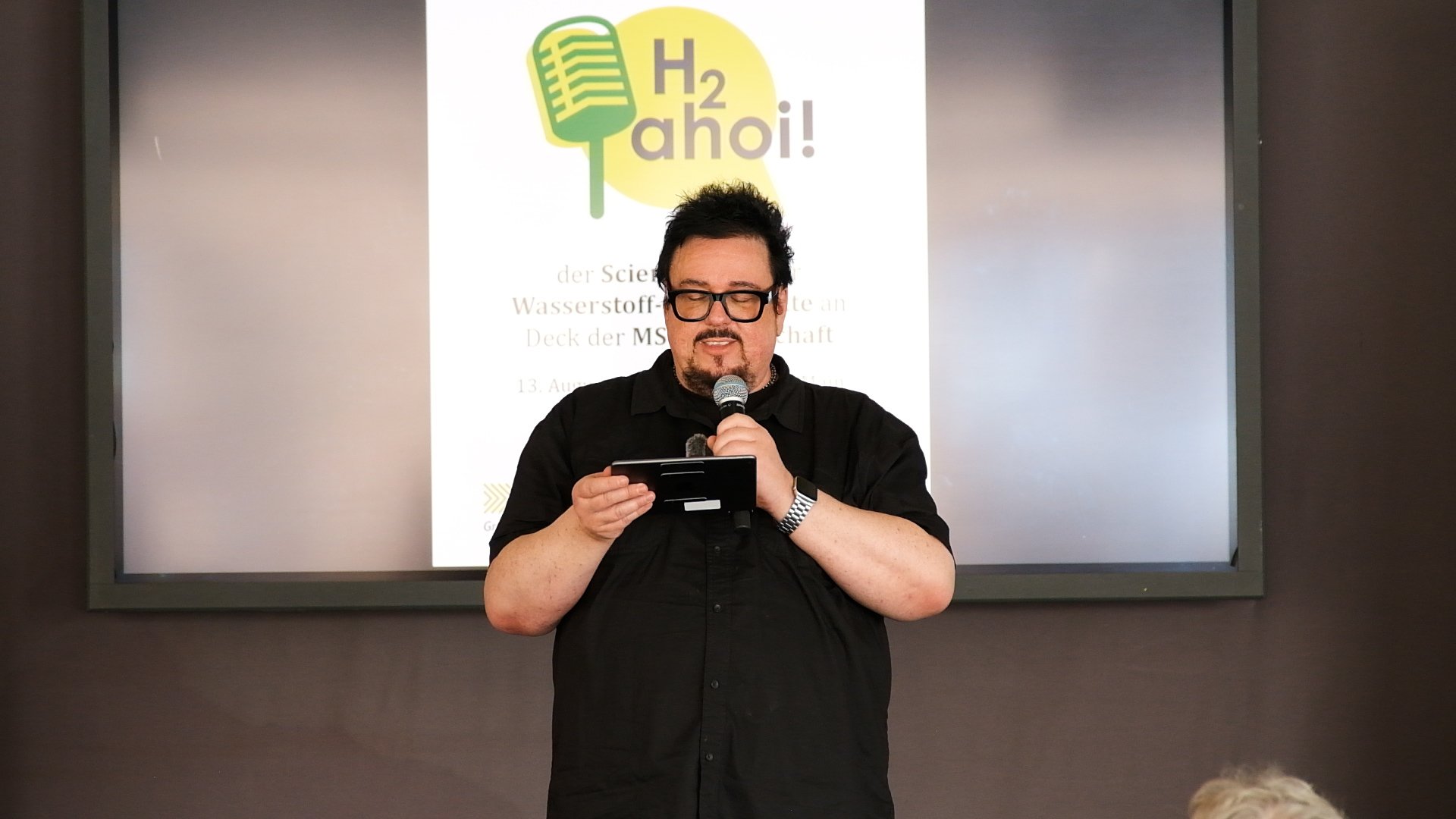 Moderator Martin Stammberger mit einem Mikrofon in der Hand.