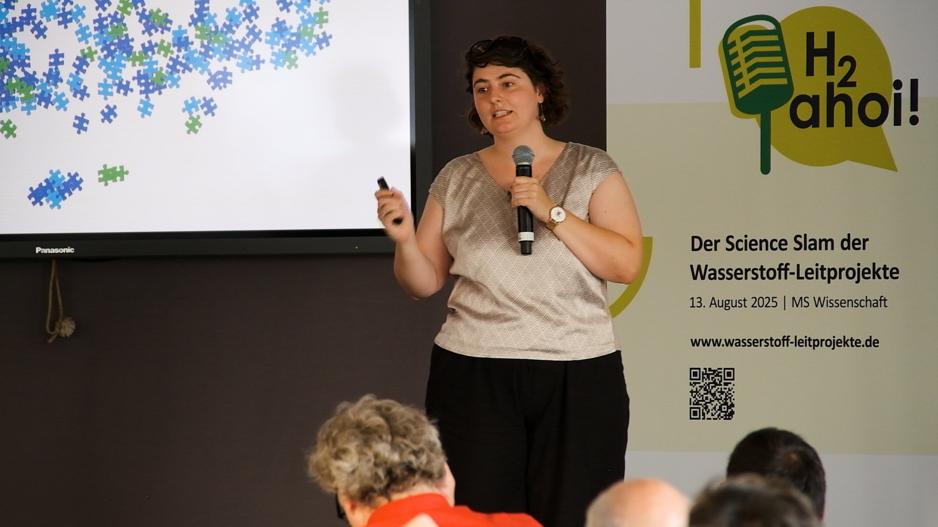 Michaela Löffler mit einem Mikrofon in der Hand vor Publikum.