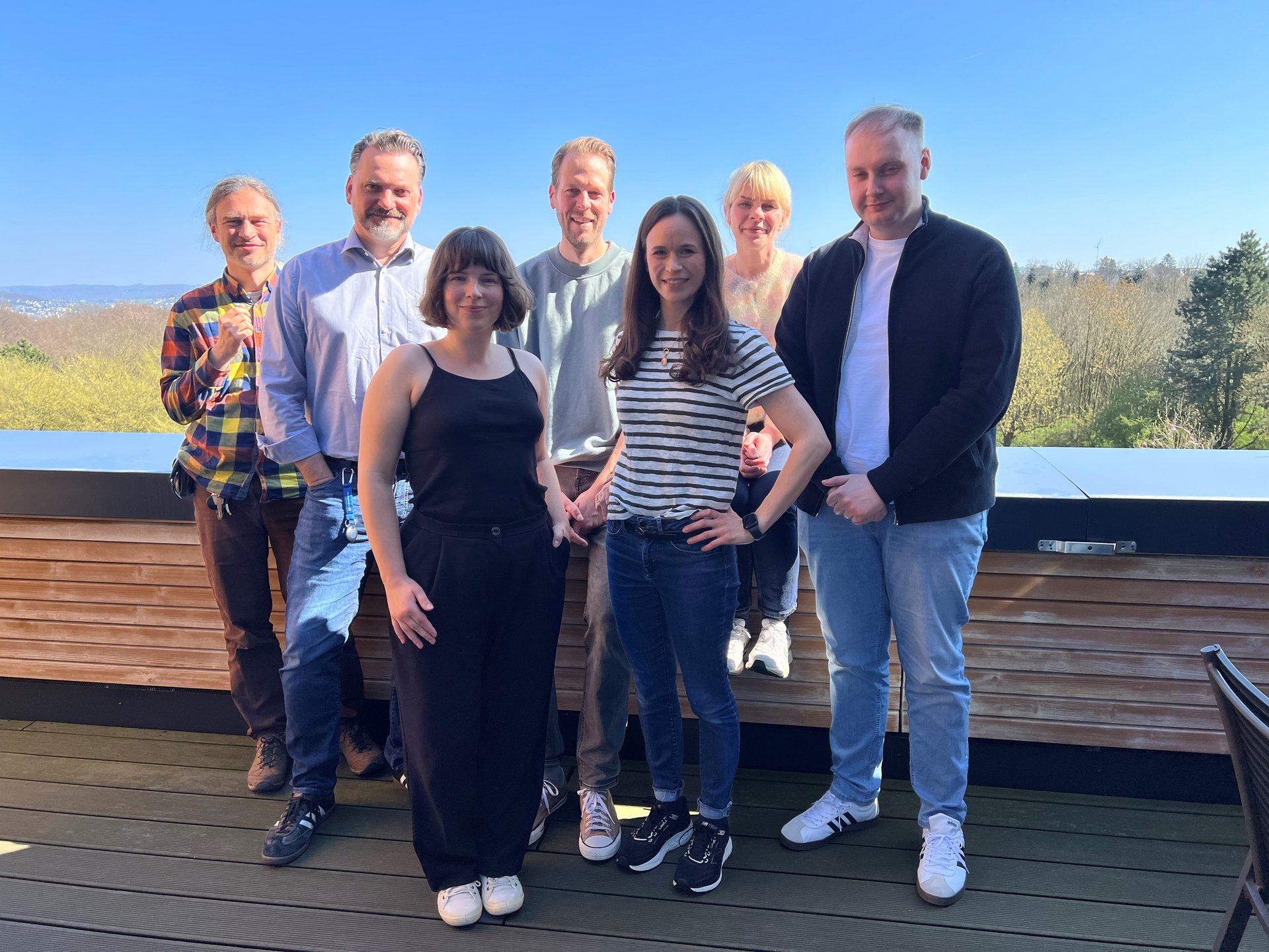 Eine Gruppe von sieben Personen gemischten Alters posiert für ein Gruppenfoto im Freien.