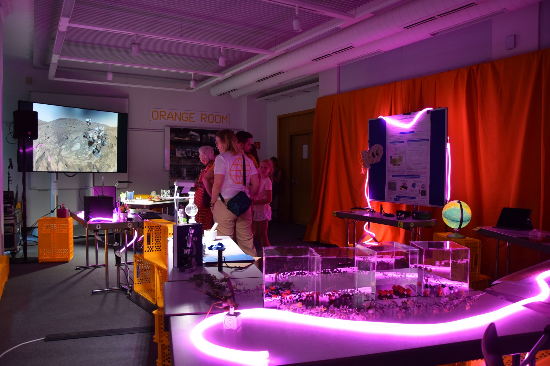 Menschen in einem Escape Room, der mit lila Neonröhren beleuchtet wird.
