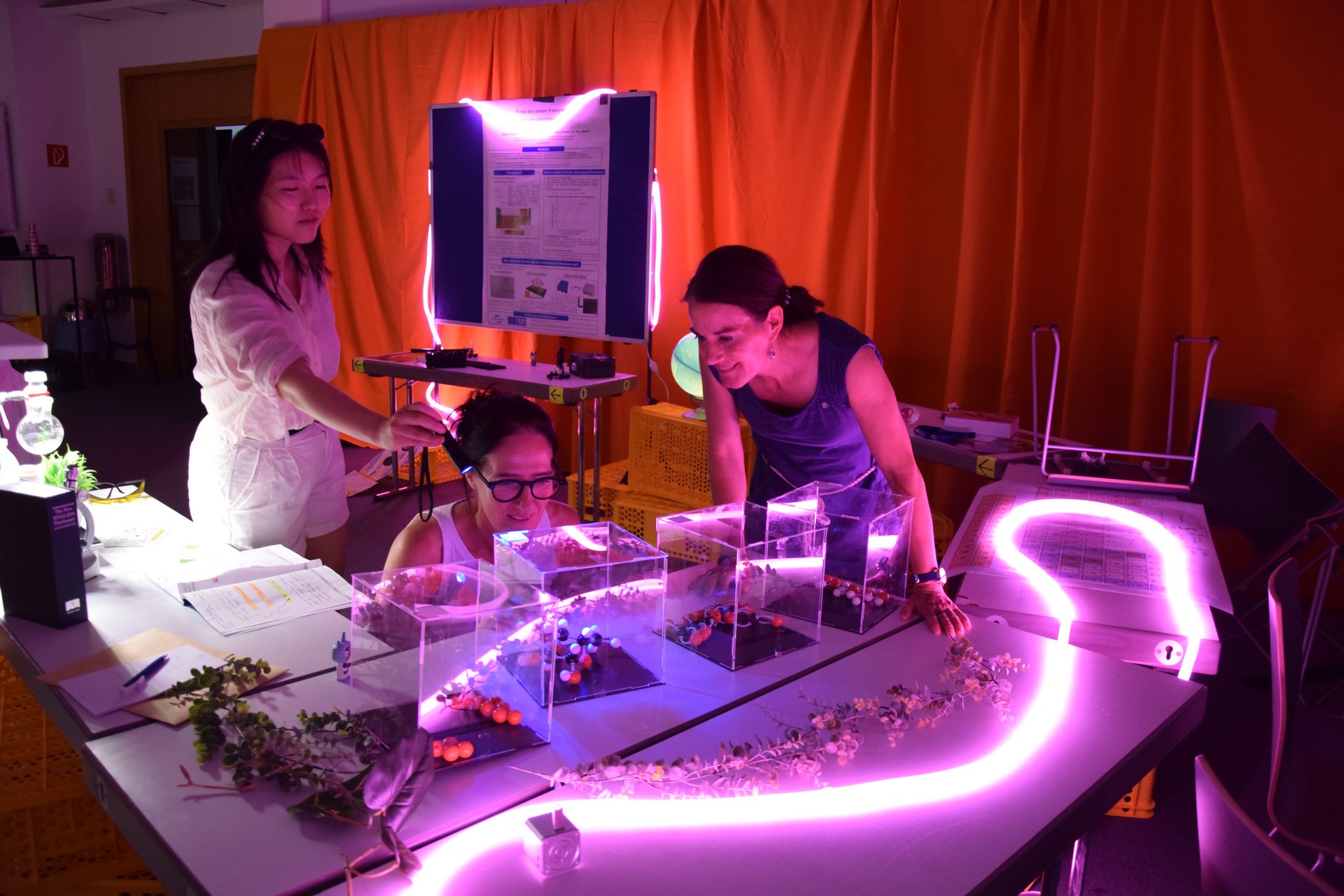 Drei junge Frauen beugen sich über einen Tisch mit chemischen Modellen.