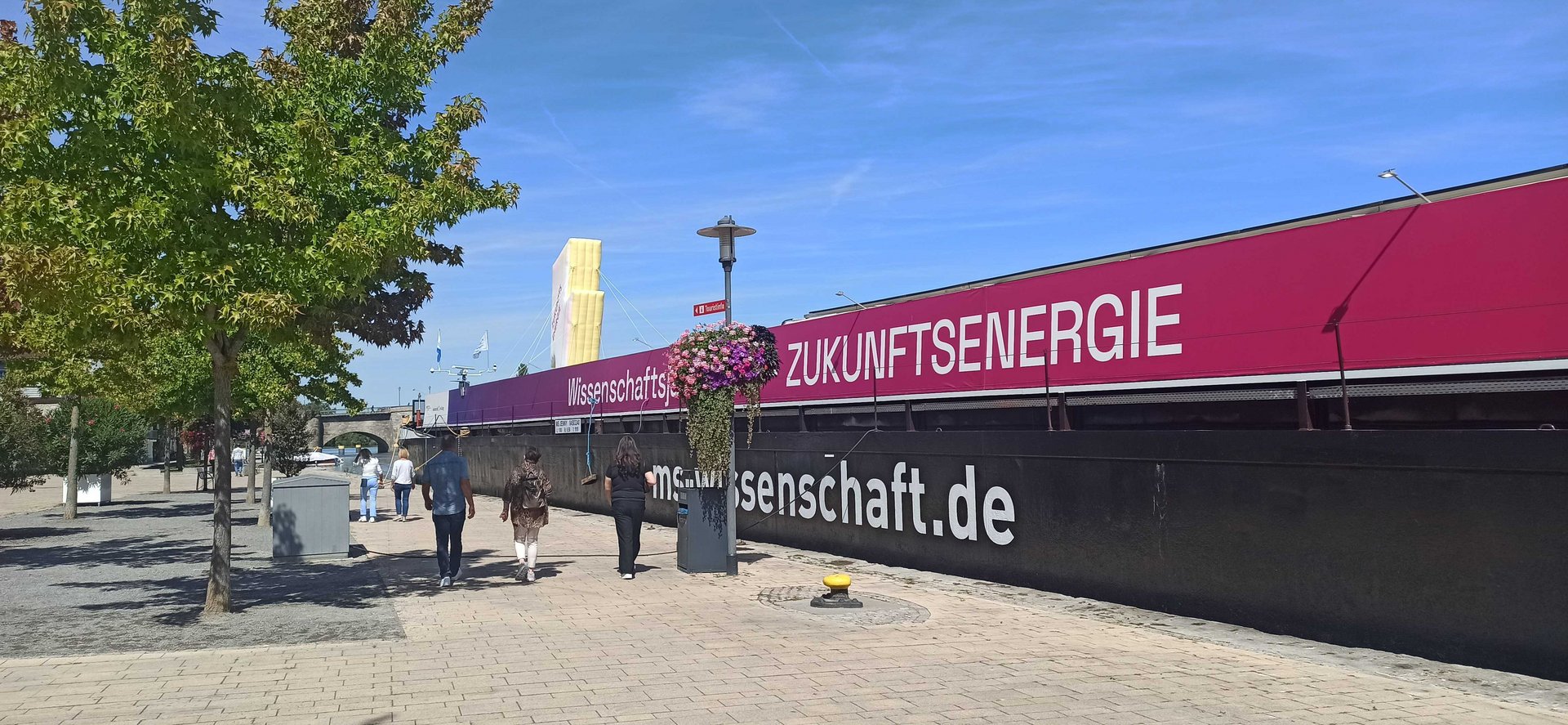 Schiff mit der Aufschrift "Wissenschaftsjahr 2025 – Zukunftsenergie" einer Uferpromenade