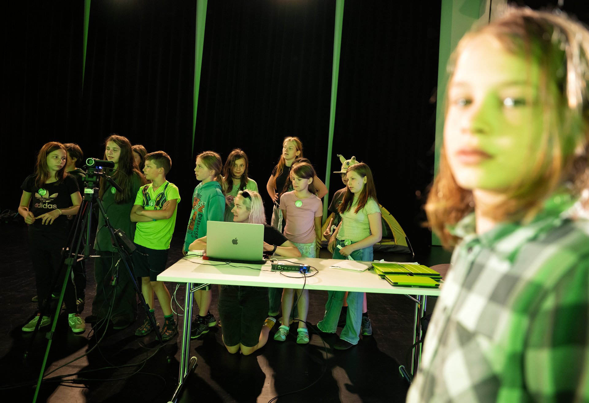 Schülerinnen und Schüler beobachten eine Aufzeichnung vorm Greenscreen.