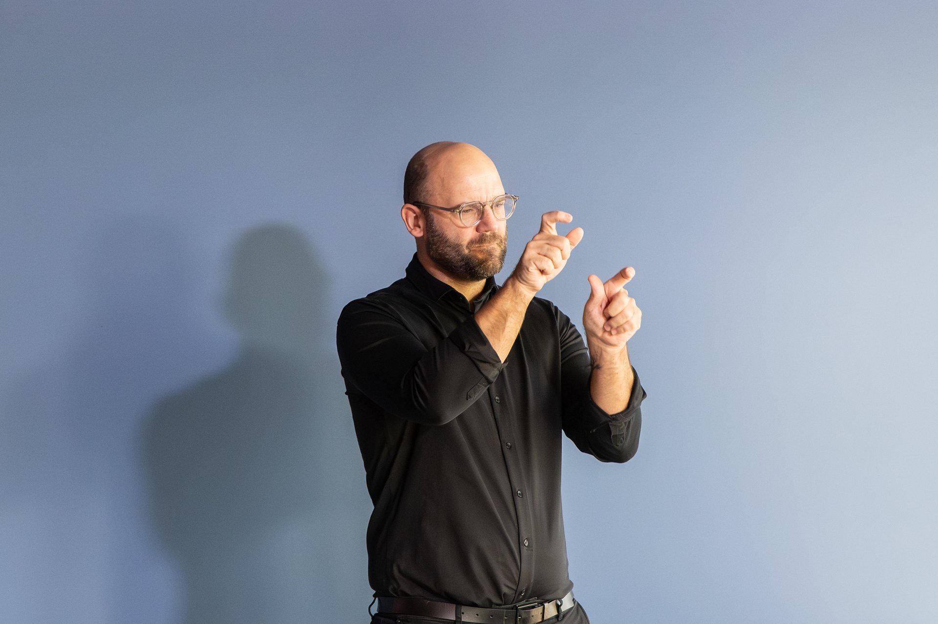 Mann steht auf einer Bühne und macht Gebärden mit seinen Händen.