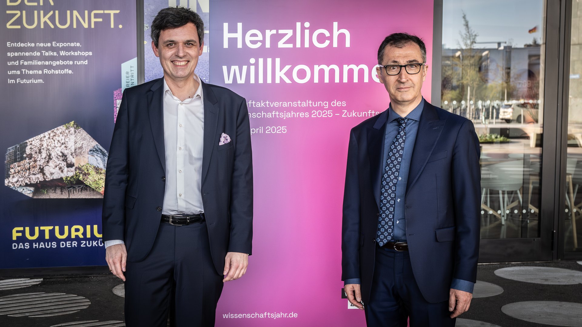 Dr. Stefan Brandt, Direktor des Futuriums, und Cem Özdemir, Bundesminister für Bildung und Forschung, stehen vor einem Roll-up mit der Aufschrift "Herzlich willkommen".