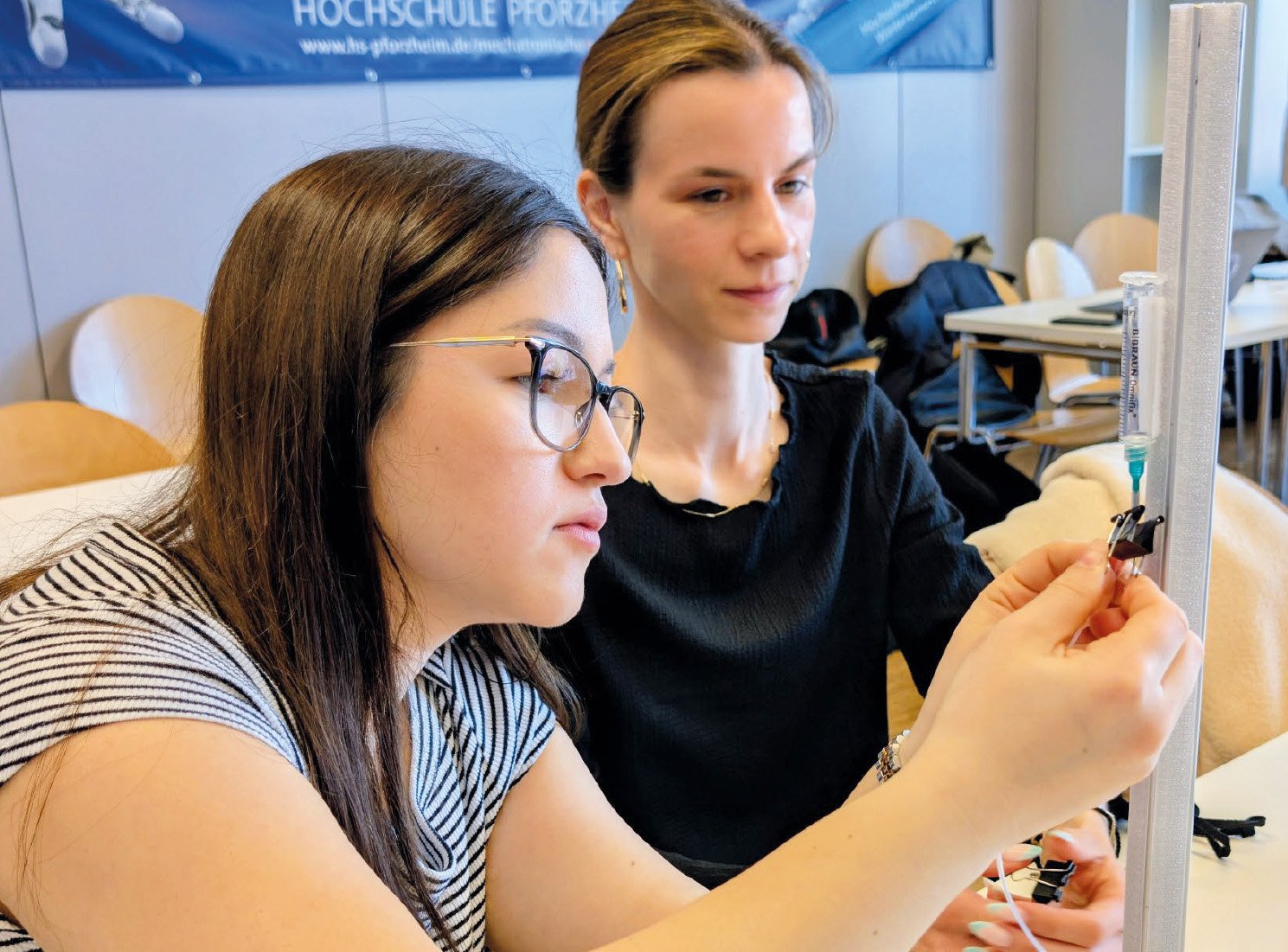 Zwei Studentinnen arbeiten an einem Katheter.