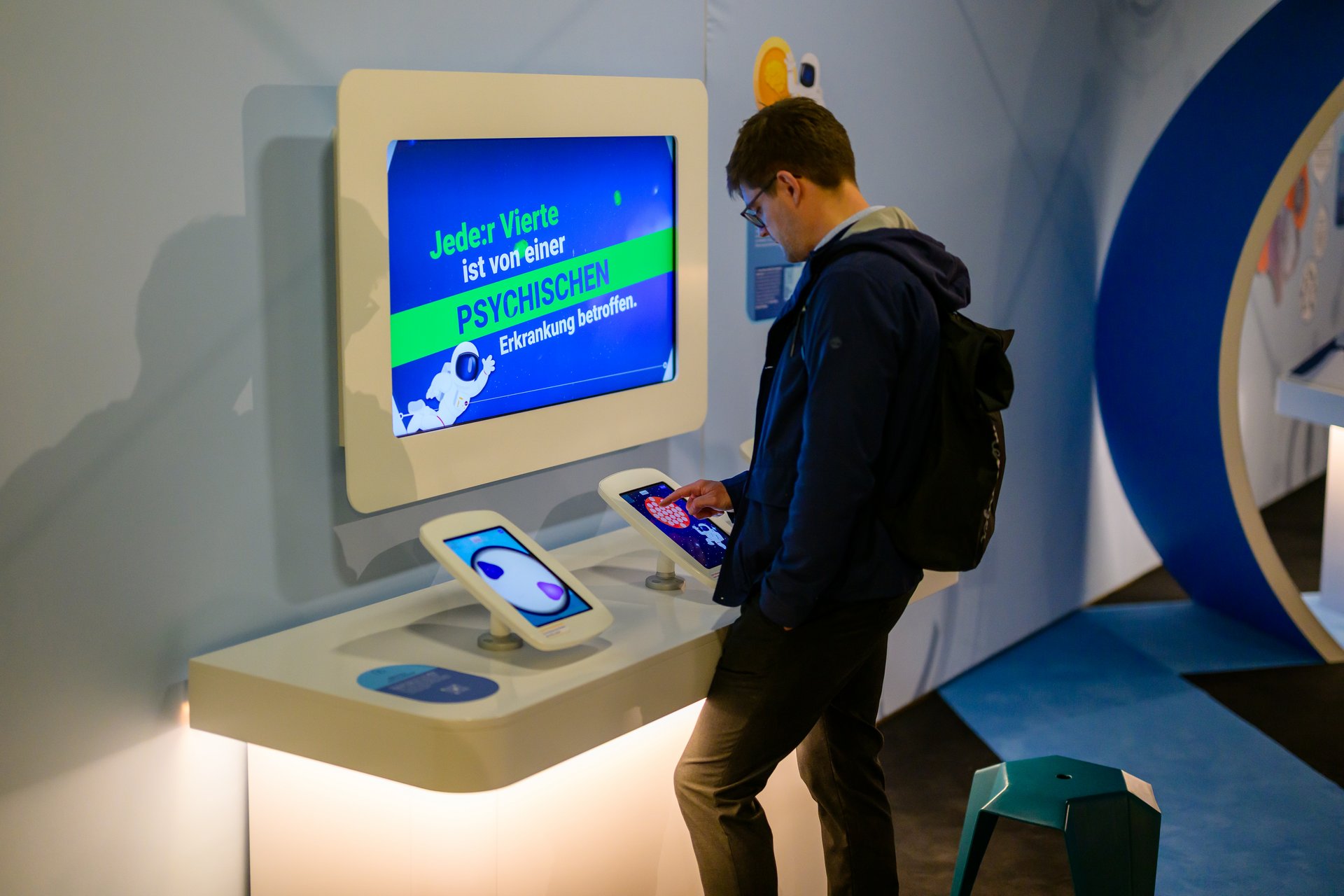 Ein Mann spielt an einem Tablet-Computer an einem der Exponate zu psychischer Gesundheit.