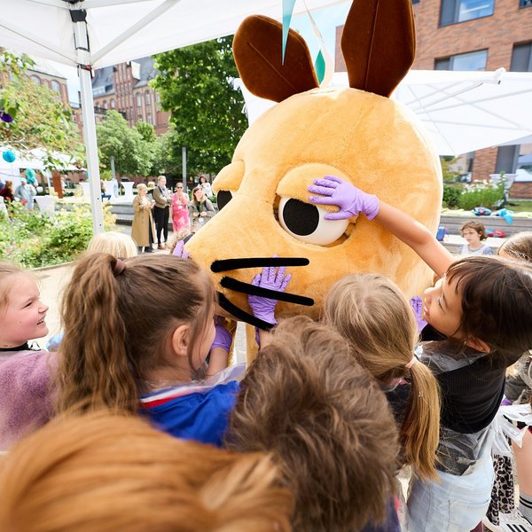 Acht Kinder streicheln die Maus als Walking Act.