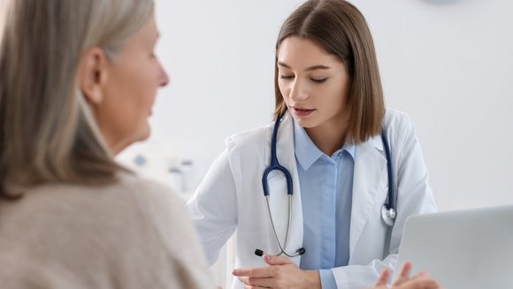 Eine ältere Patientin sitzt mit einer Ärztin am Tisch.