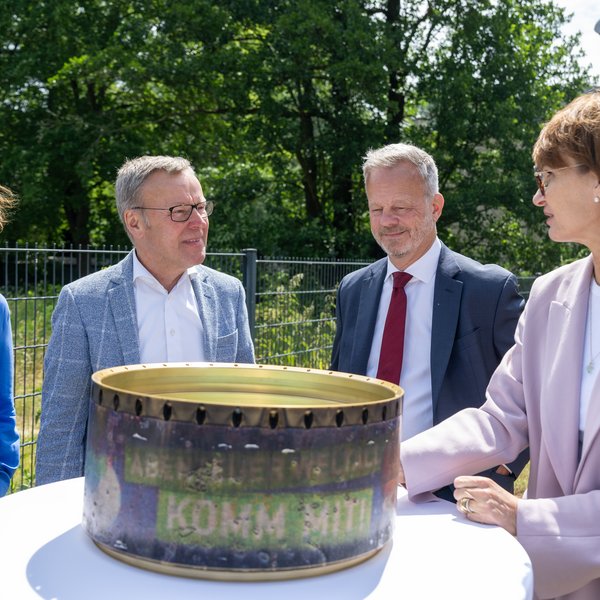 Vier Personen stehend an einem Tisch, draußen