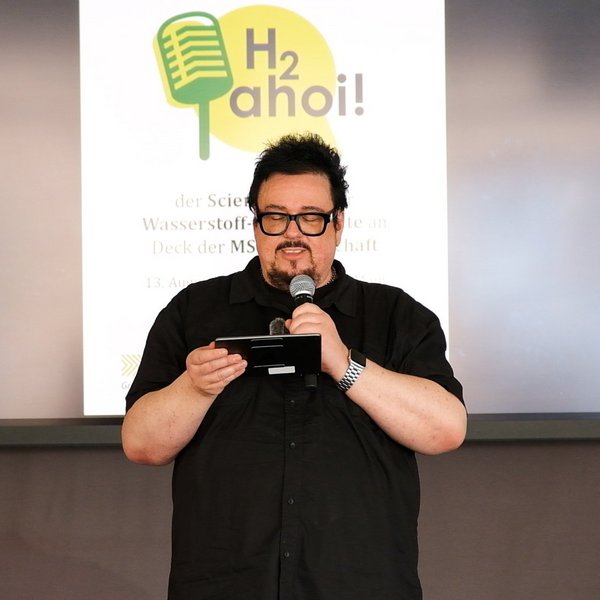 Moderator Martin Stammberger mit einem Mikrofon in der Hand.