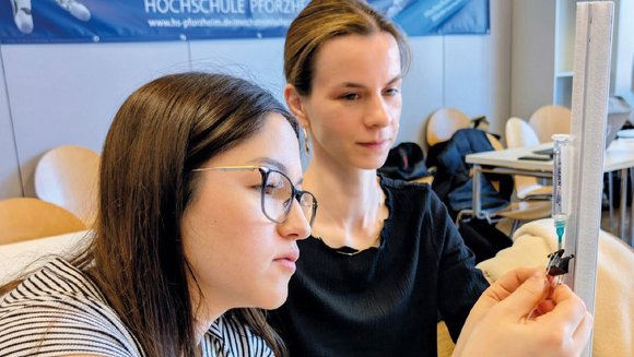 Zwei Studentinnen arbeiten an einem Katheter.