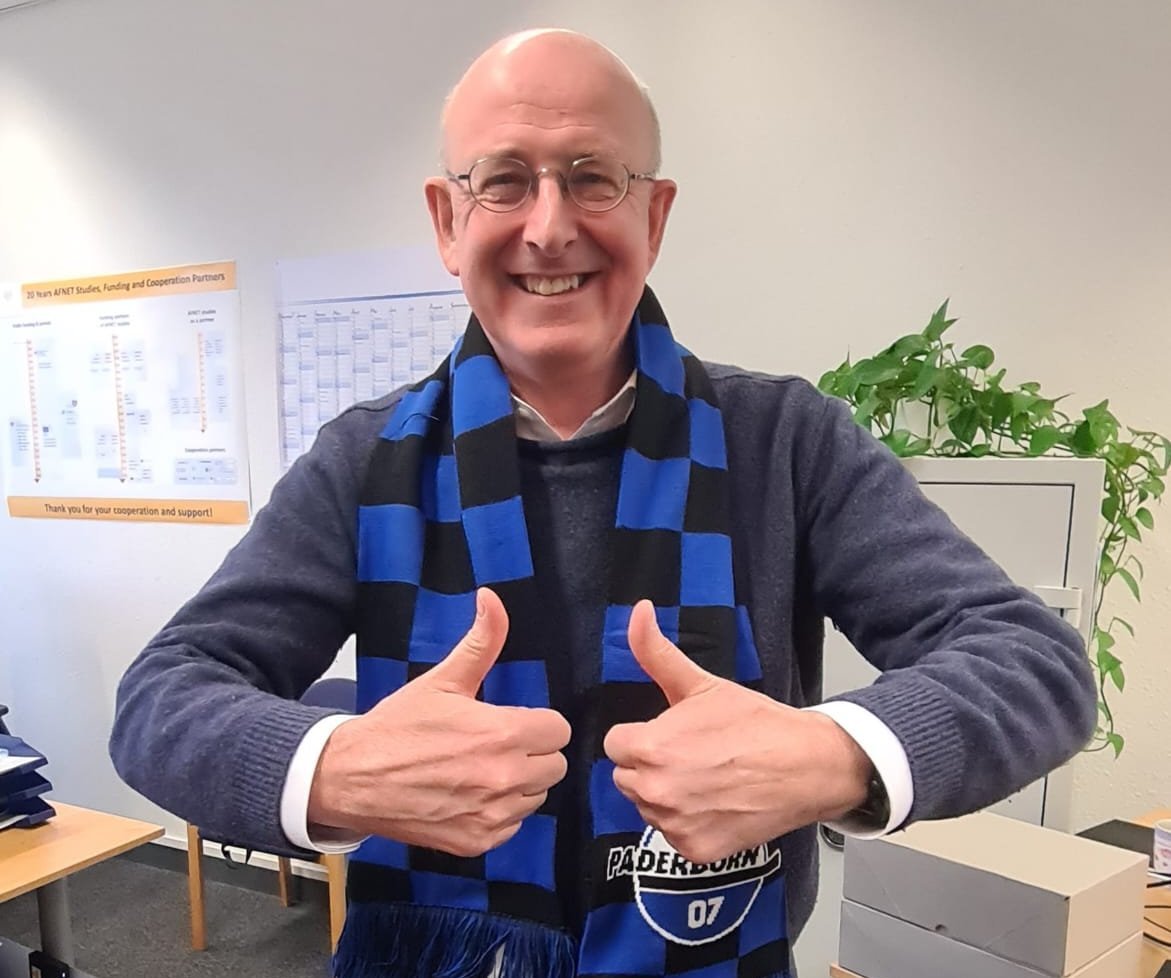 Porträt Prof. Dr. med. Andreas Goette (Projektleiter FanBeats und Kardiologe), streckt beide Daumen nach oben und lächelt in die Kamera. Er trägt einen Schal des SC Paderborn 07. 