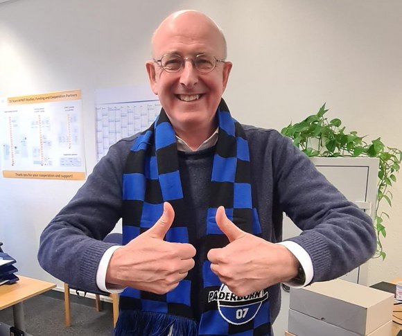Porträt Prof. Dr. med. Andreas Goette (Projektleiter FanBeats und Kardiologe), streckt beide Daumen nach oben und lächelt in die Kamera. Er trägt einen Schal des SC Paderborn 07. 