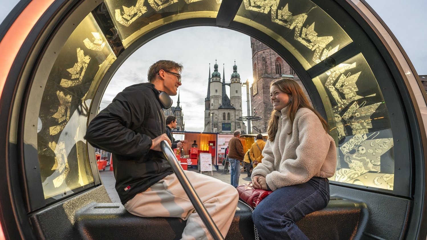 Zwei Personen sitzen sich auf einer Bank gegenüber, über die ein beleuchteter Bogen gespannt ist