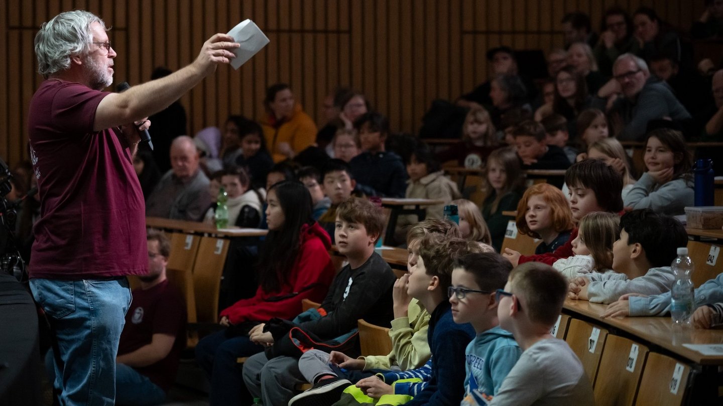 Moderator spricht vor Publikum.