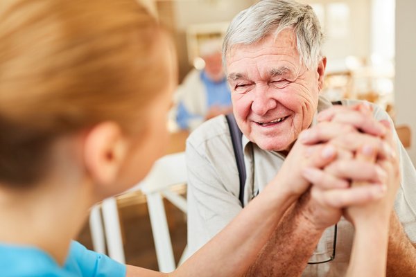 Frau hält Hand von einem lächelnden älteren Mann