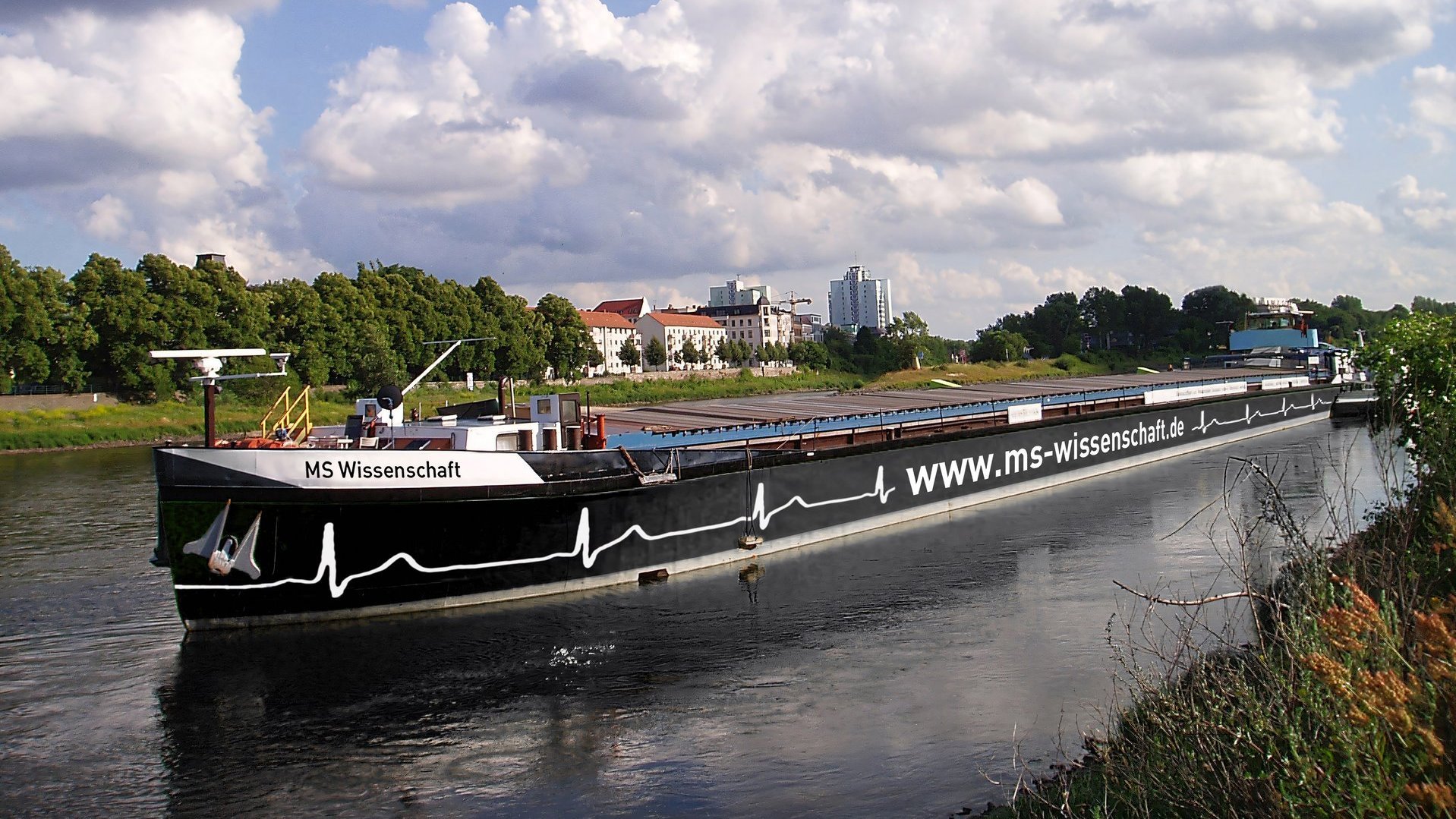 Frachtschiff mit der Aufschrift "www.ms-wissenschaft.de" auf einem Fluss