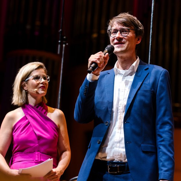 Moderatorin und Wissenschaftler auf der Bühne der Kölner Philharmonie beim Konzert von Noten und Neuronen
