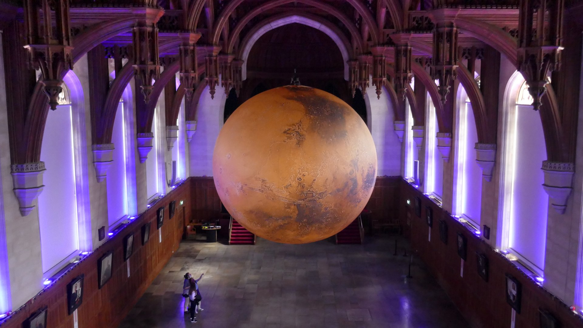 Foto von einem großen Nachbild vom Mars, welches in einer Ausstellungshalle hängt. 