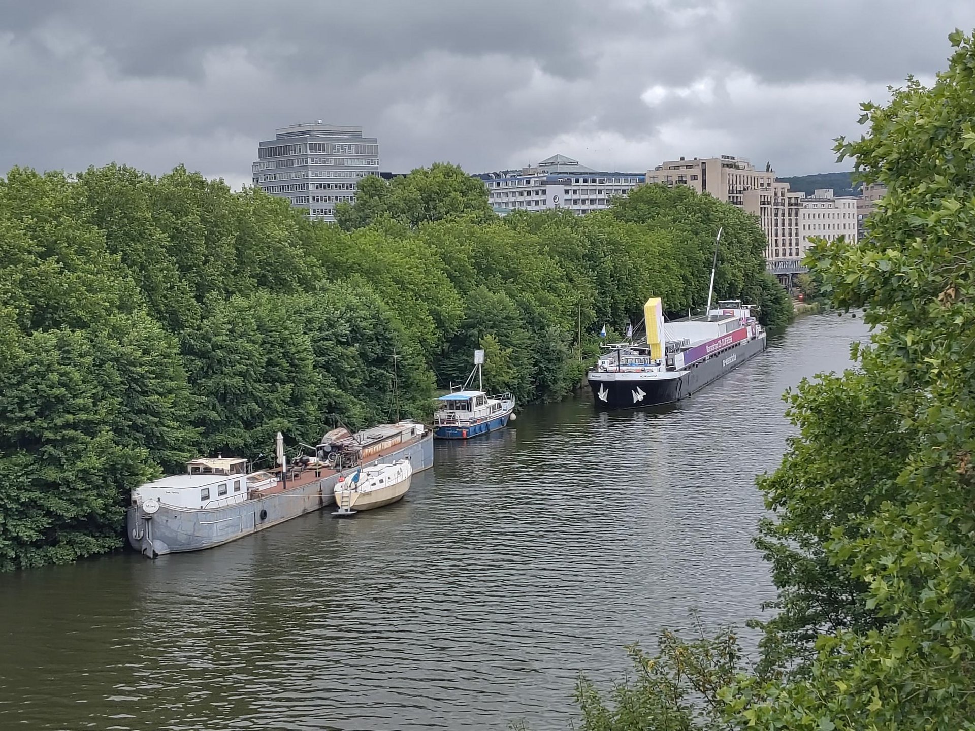 Luftaufnahme von vier Schiffen und Booten, die an einem stark begrünten Ufer vor Anker liegen