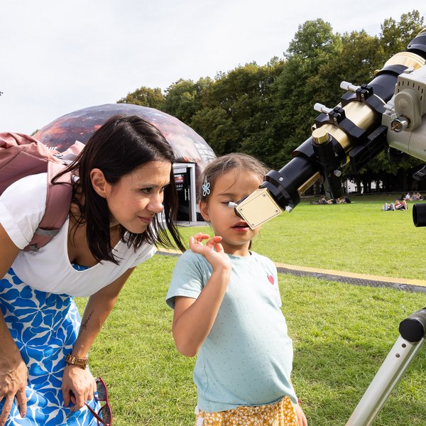 Eine Frau und ein Kind schauen durch ein Teleskop 