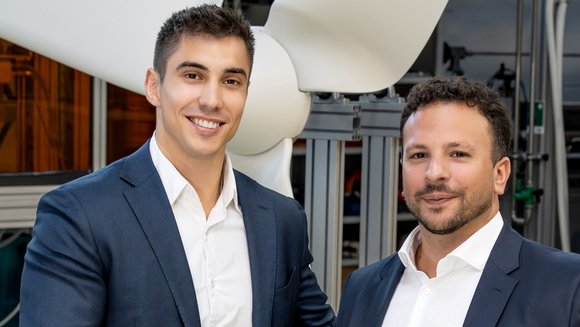 Links Geschäftsführer der BBF Gruppe, rechts Leiter Simulation und Auslegung im Forschungsbereich Polymermaterialien und Composite des Fraunhofer IAP. Beide Männer lächeln in die Kamera. Im Hintergrund Prototyp der Kleinwindkraftanlage.