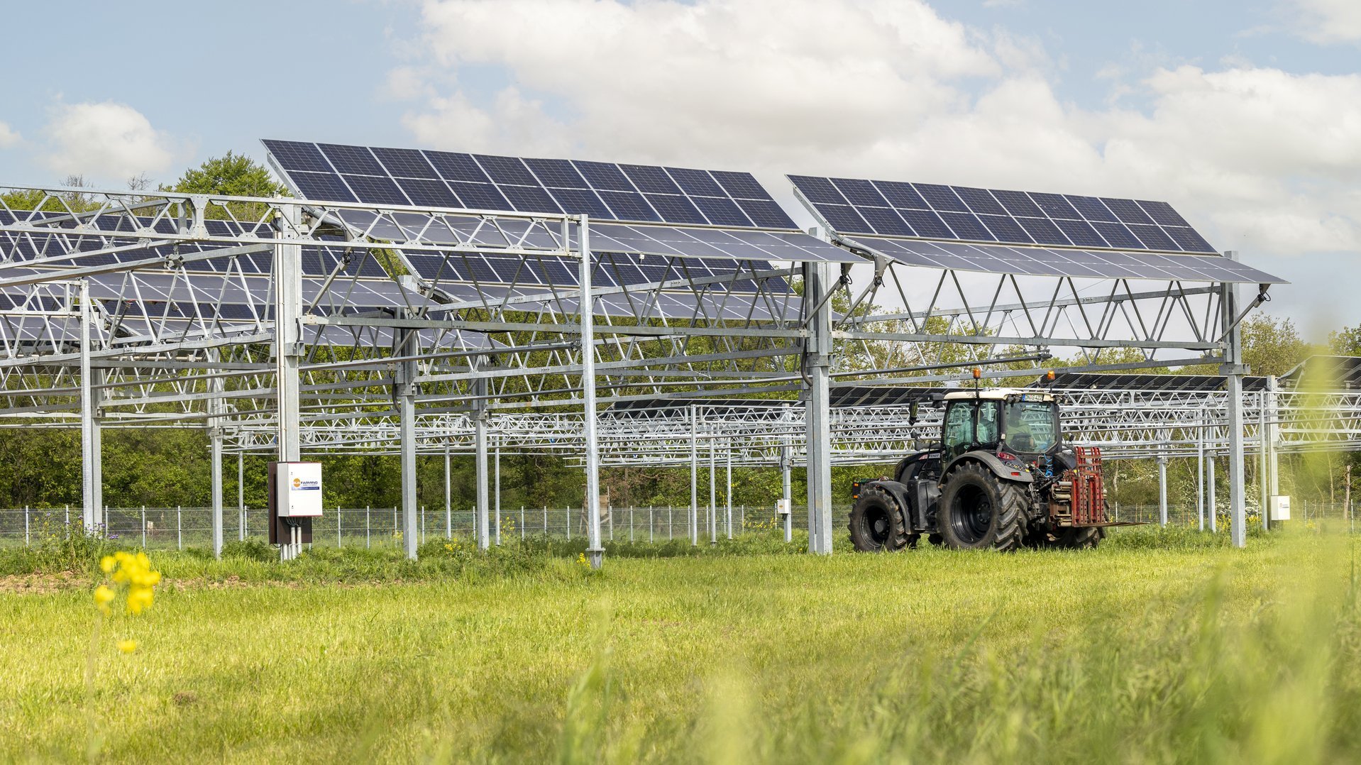 Ein Trecker fährt unter Agri-PV-Anlagen hindurch.