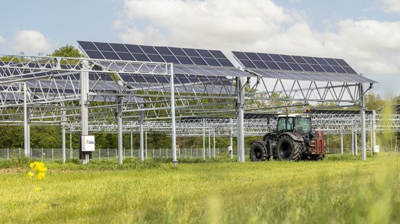 Ein Trecker fährt unter Agri-PV-Anlagen hindurch.