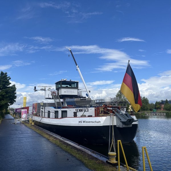 Schiff mit Deutschlandfahne und Aufschrift "MS Wissenschaft" liegt an Ankerplatz