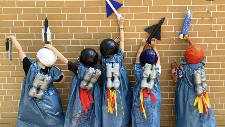Kinder in selbstgebastelten Kostümen mit Raketen auf dem Rücken