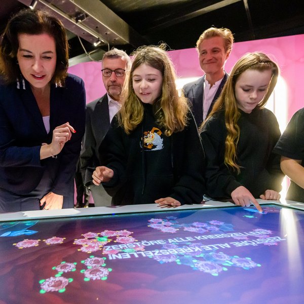Bundesministerin für Forschung, Technologie und Raumfahrt Dorothee Bär spielt mit Kindern an einem großen Touchscreen.