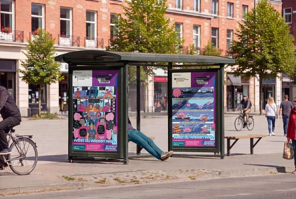 Bushaltestelle mit Plakaten, auf denen Comic-Figuren abgebildet sind und der Text: Willst du wissen wie?