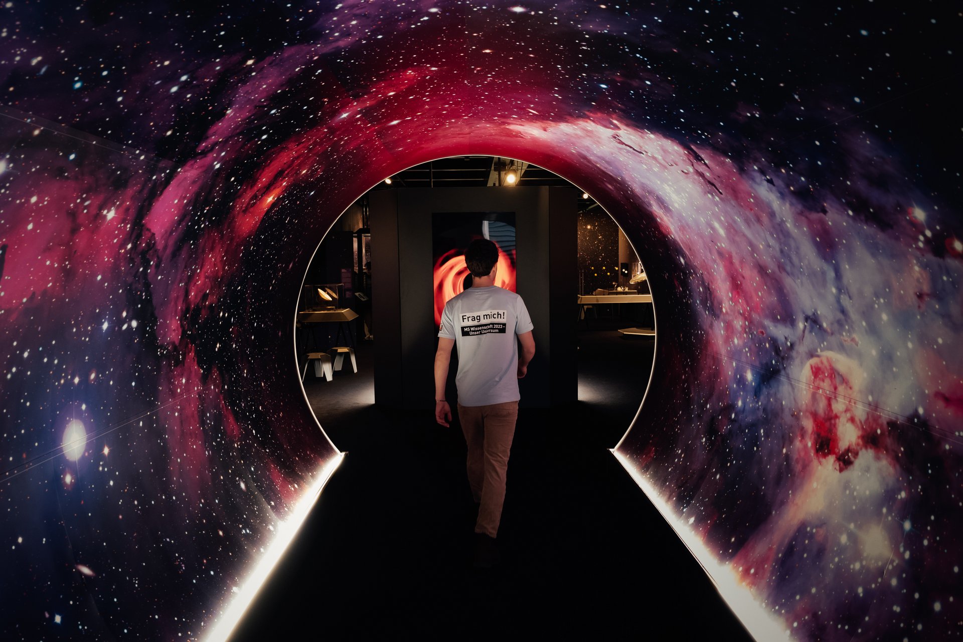 Eine Person läuft durch einen Tunnel mit Weltraumaufdruck in der Ausstellung
