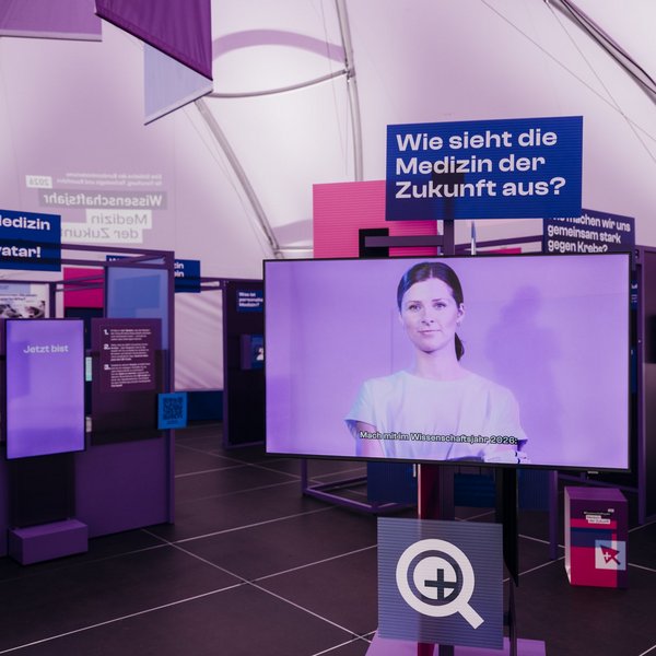 Innenraum einer Ausstellung mit verschiedenen Tafeln und Bildschirmen, zu lesen sind die Überschriften "Erkunde die Medizin der Zukunft – mit deinem Avatar!" und "Wie sieht die Medizin der Zukunft aus?"