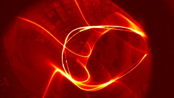 Leuchtendes Plasma: Rot-orangenes Plasma in ringförmiger Bewegung innerhalb einer Fusionsanlage.